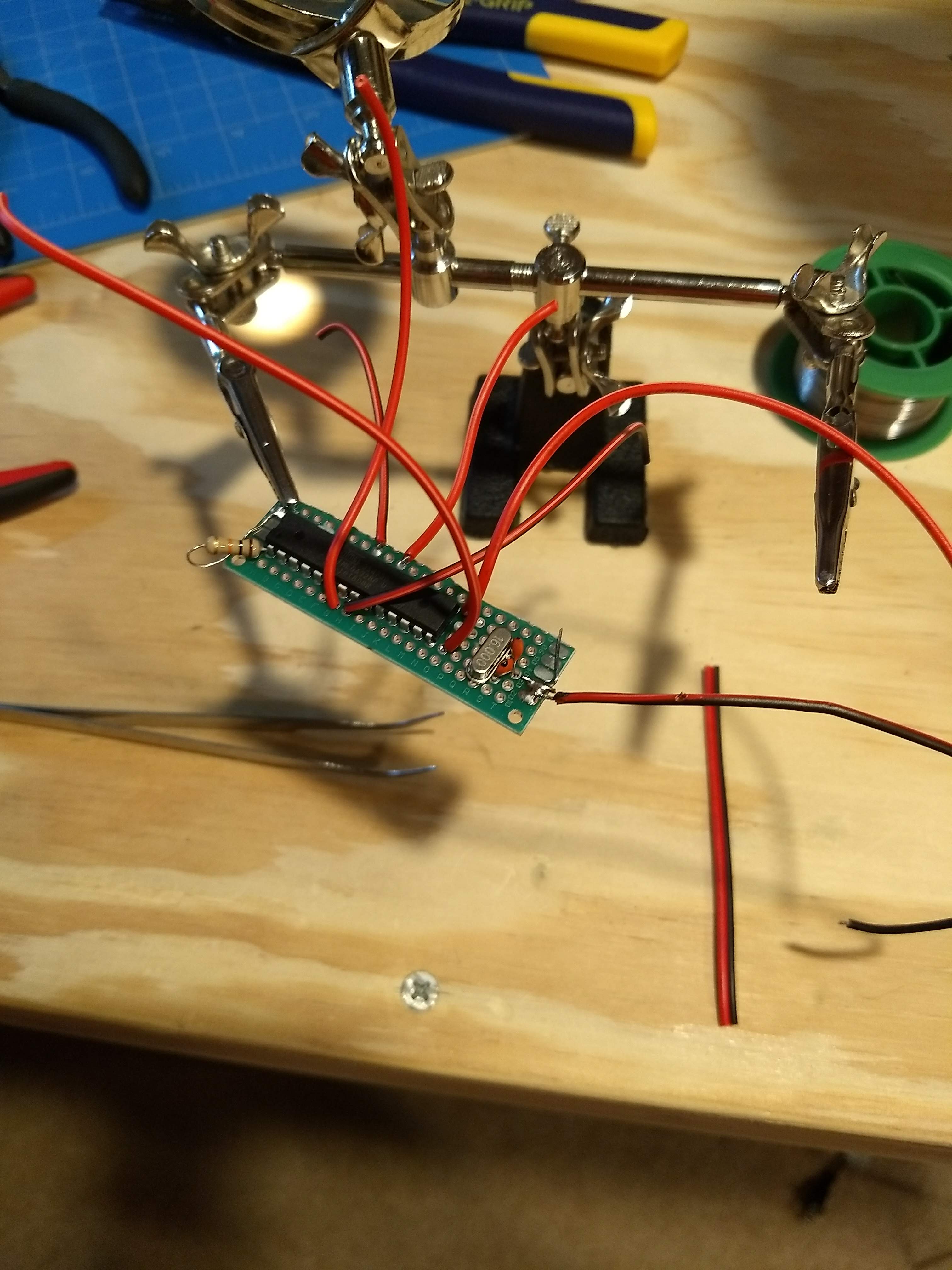 An ATMEGA328p-pu microcontroller and clock soldered onto a plain PCB board with wires attached