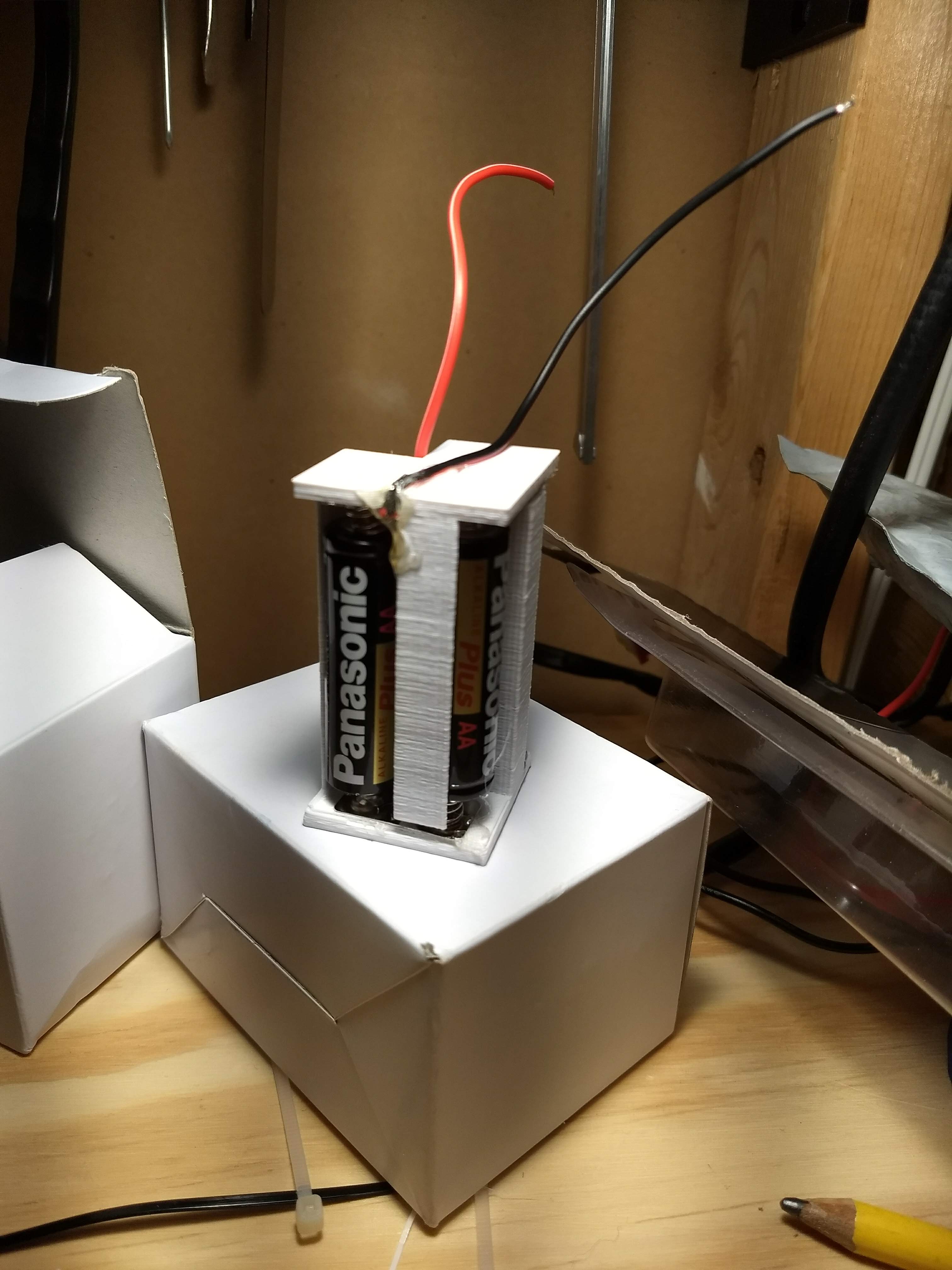 Three AA batteries connected to a 3D-printed housing with metal connectors and wires protruding